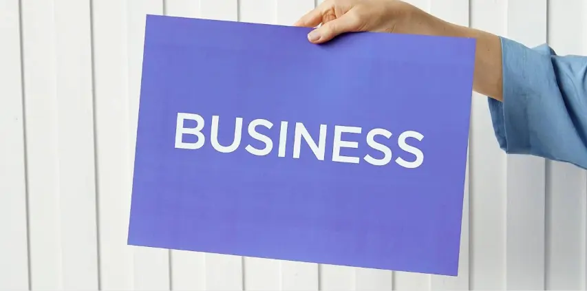 Printed business sign held against a white wall